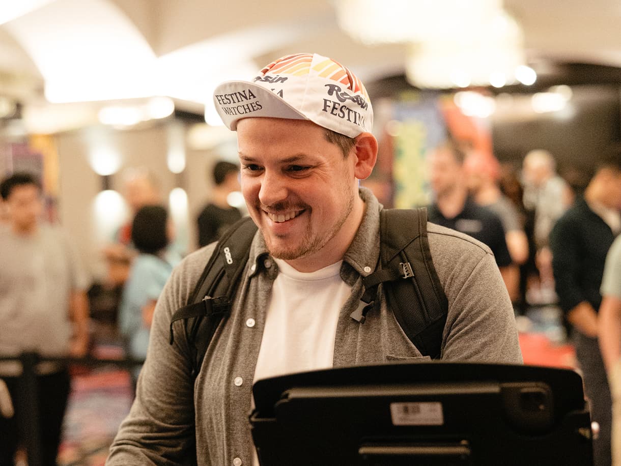 A smiling attendee checking in at a self-service kiosk at dbt Summit 2026