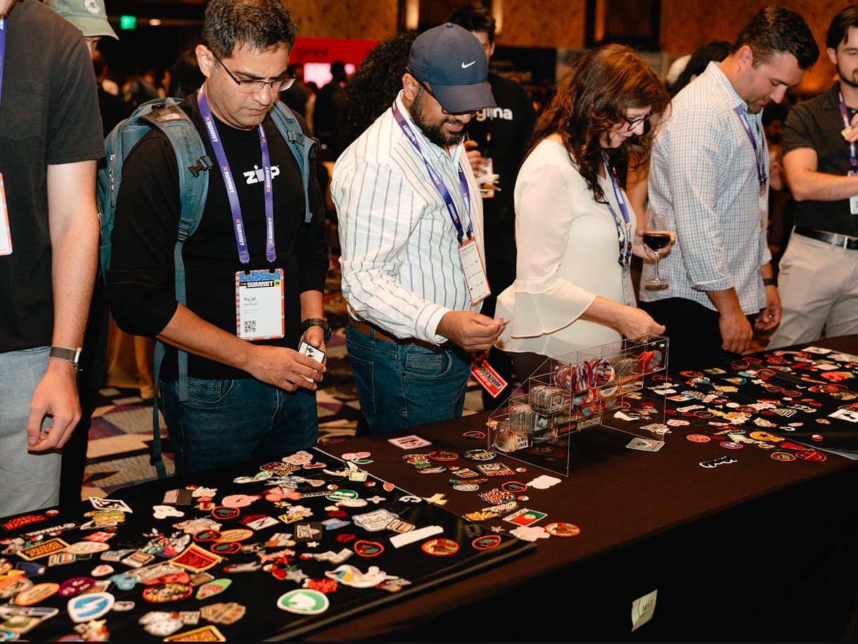 Attendees browsing a table covered in pins and stickers at dbt Summit 2026